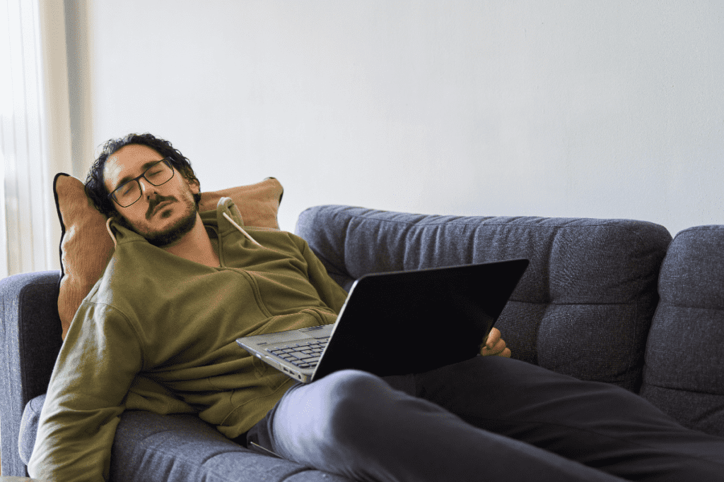 A man sleeping on sofa with laptop