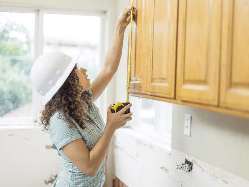 A woman measuring kitchen for remodeling
